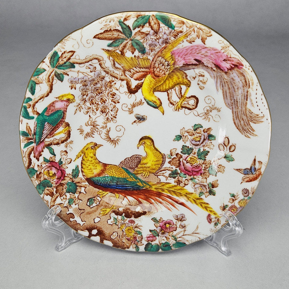 Royal Crown Derby Olde Avesbury bone china plate with richly coloured exotic birds and floral decoration on a white ground with gold rim, displayed on a plate stand
