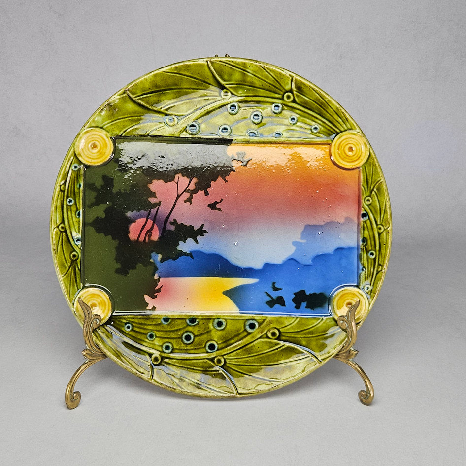 Schütz Cilli majolica landscape wall plate model 887, green relief border with painted sunset scene, Central European antique ceramics