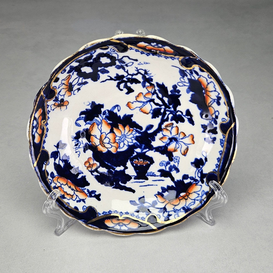 Blue floral saucer with orange accents and scalloped edge