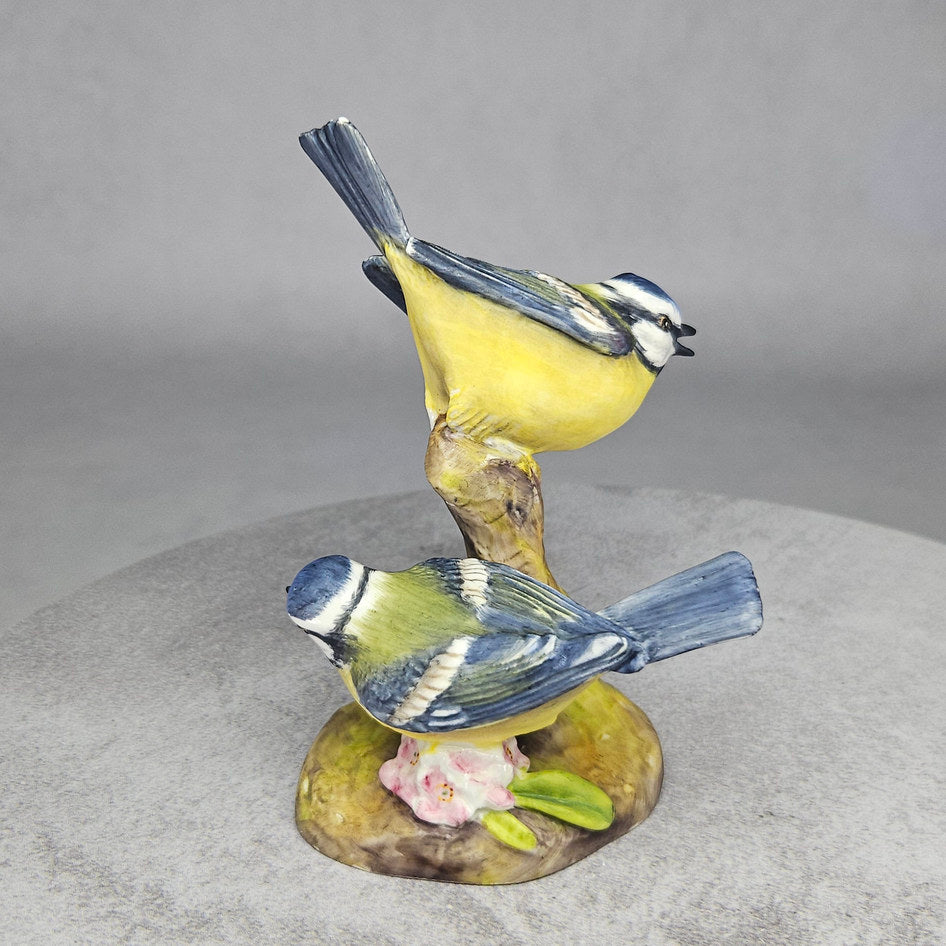 Pair of blue tits figurine on tree trunk base, rear view
