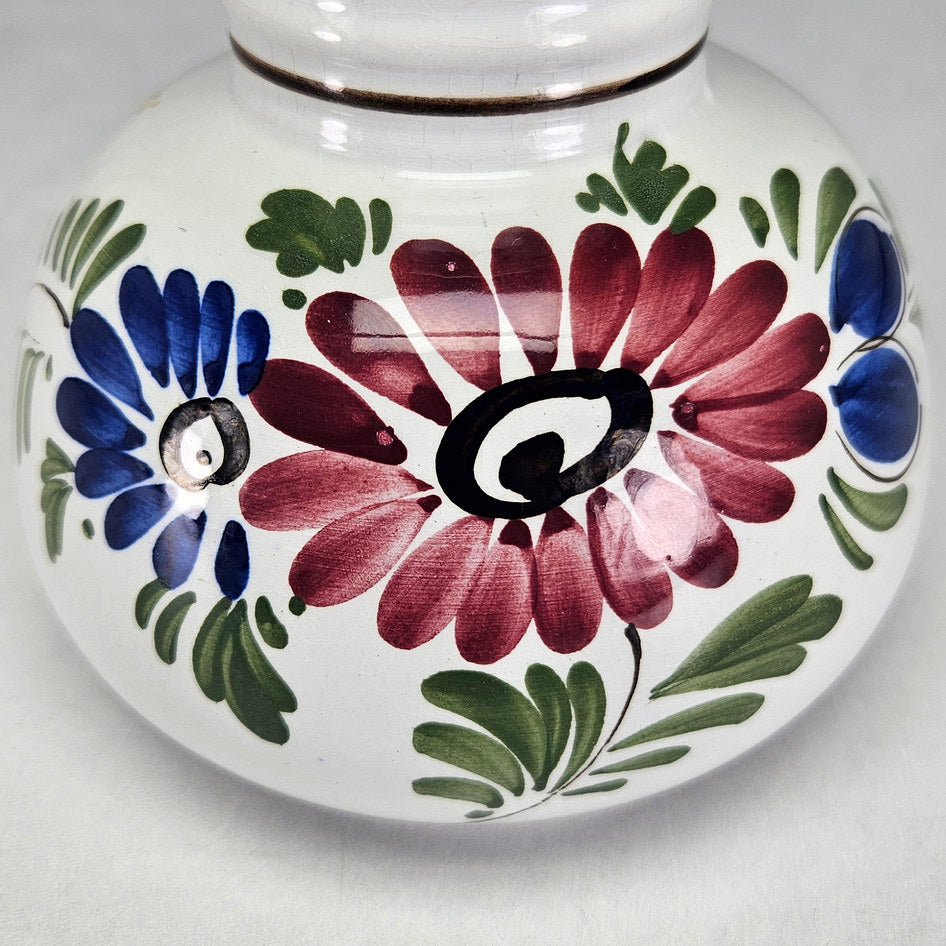 Dutch polychrome vase close-up of burgundy flowers and green leaves