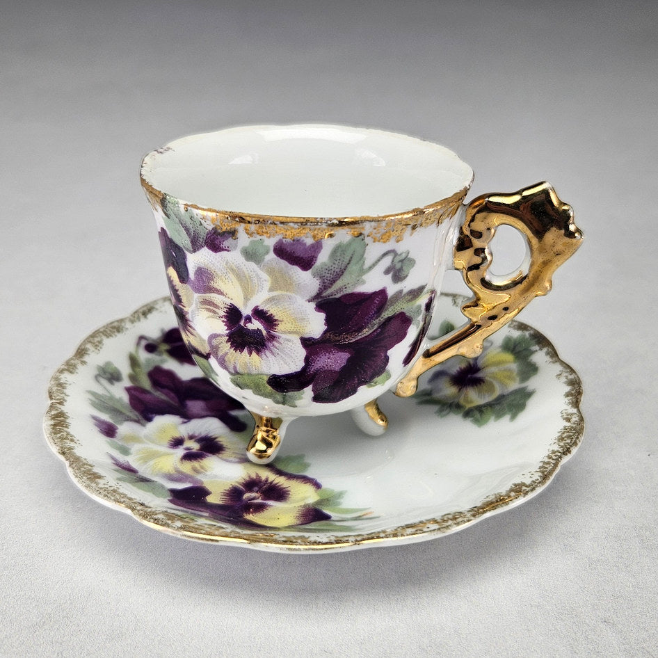 Unmarked footed porcelain cup and saucer with pansies