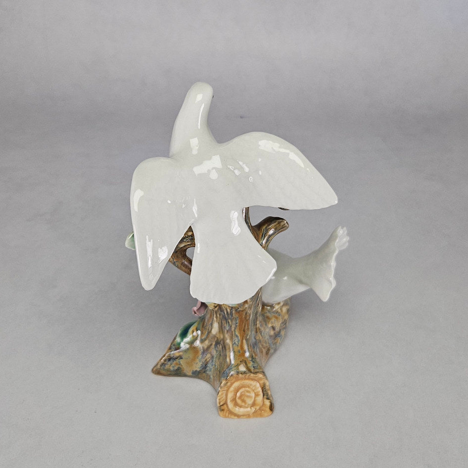 Pair of white doves on tree trunk base, rear view